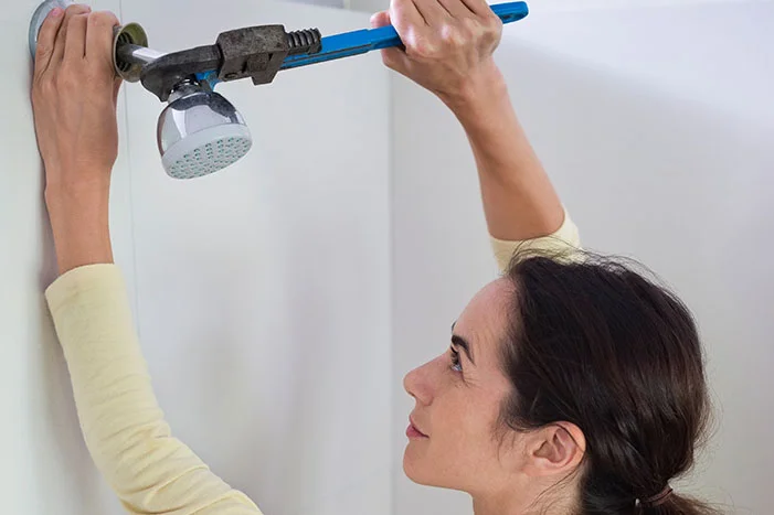 Person montiert Duschkopf mit Rohrzange.